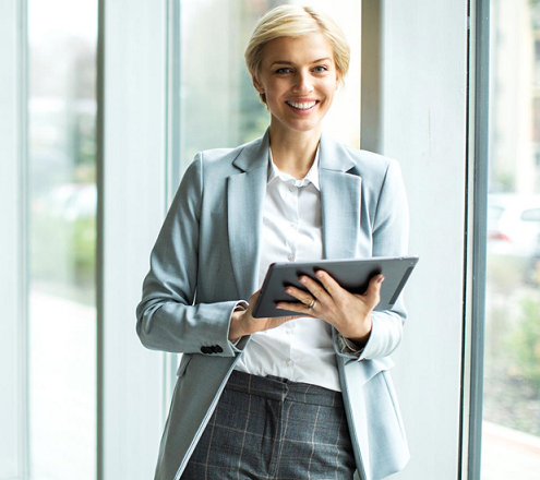 Woman with black curly hair wearing a backpack in a hallway holding and about to tap a phone